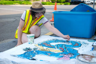 Artist Indra Hunter painting during the 2022 UpStream Art project