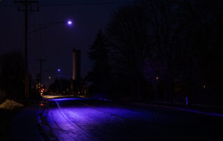 A photo of a street illuminated by an LED streetlight that has turned purple