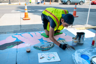 UpStream Art Artist Henry Stubbert working on storm drain mural in July 2022