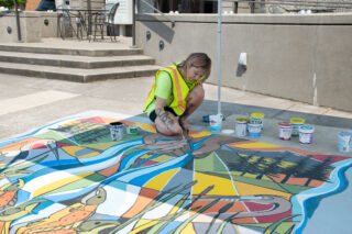 Artist Marlis painting during the 2022 UpStream Art project