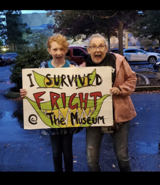 Community members with "I survived Fright at the Museum" sign in 2022